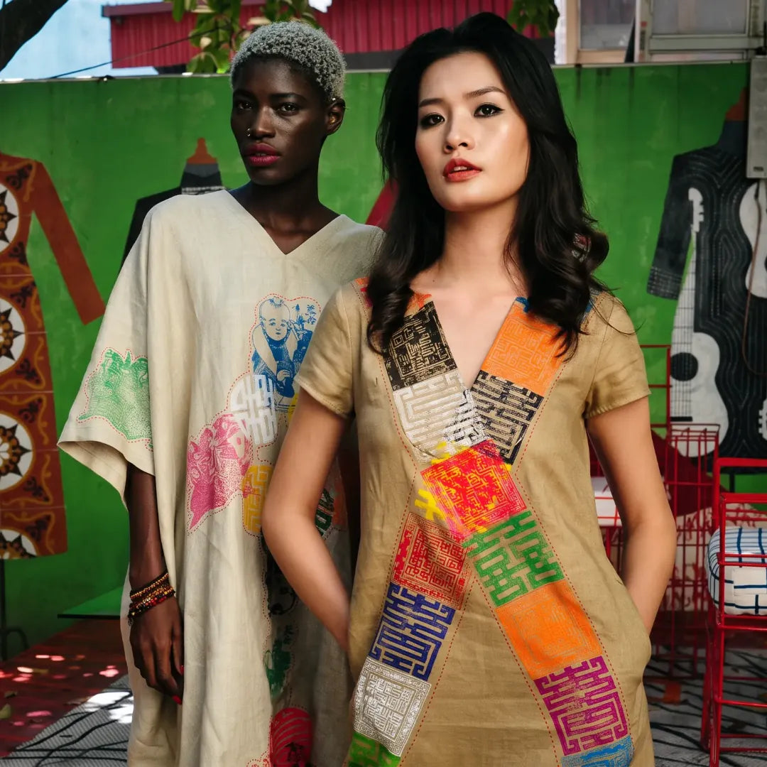 Two models in linen pieces appliqued with hand-painted Vietnamese characters, before a green wall