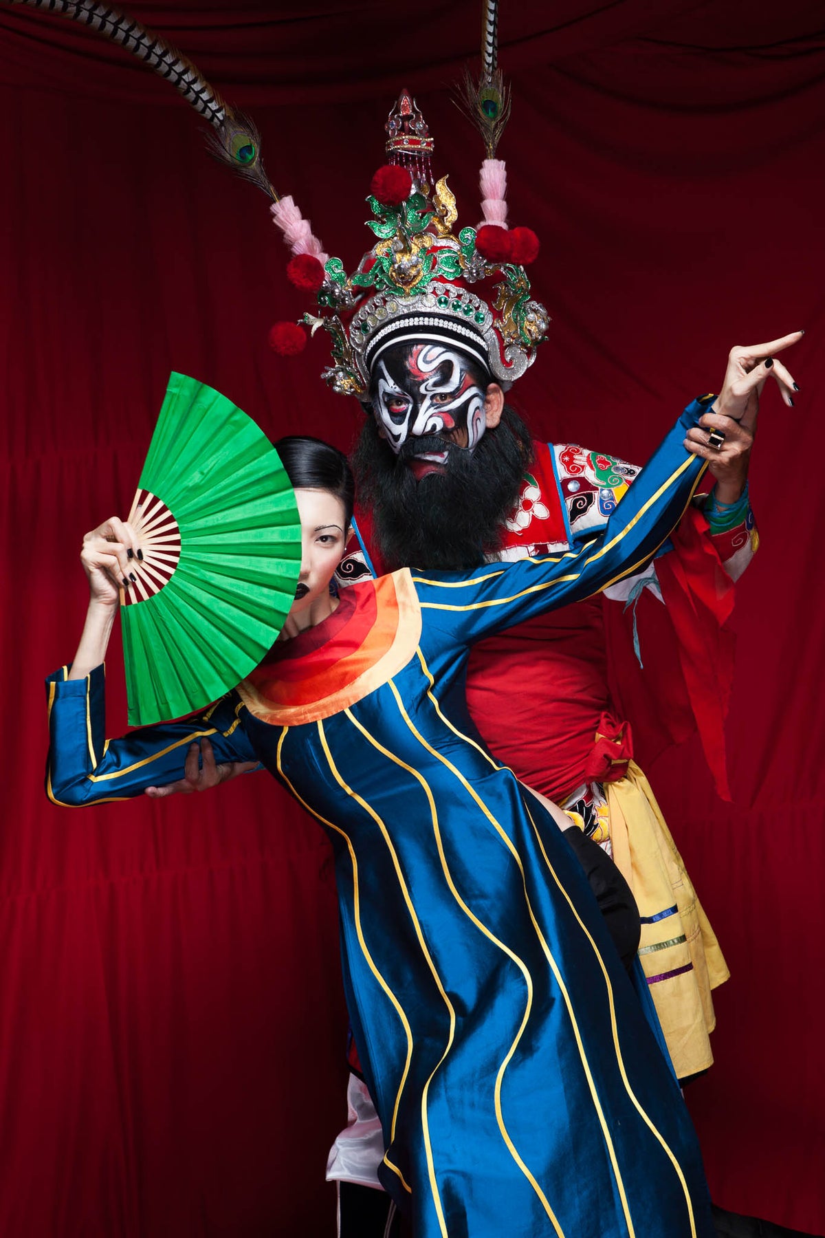 Model with a red fan in a hand-painted robe and opera headdress