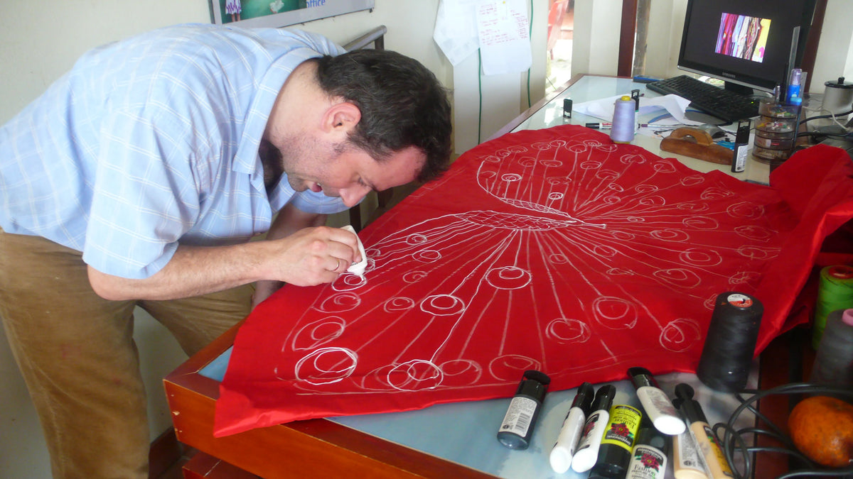 Diego Cortizas drawing a design in white onto red cloth, 2006