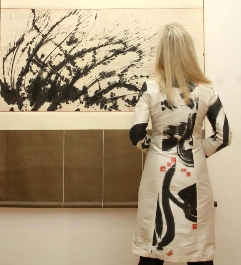 A visitor in a black and white Chula dress before a large brushwork painting, 2009