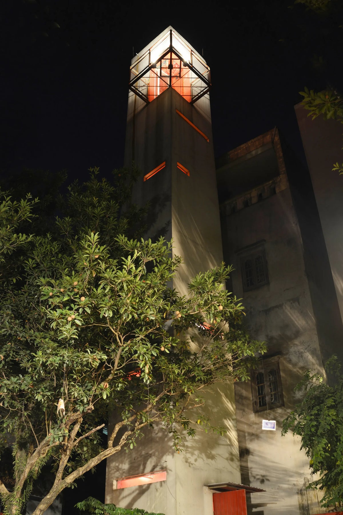 The 3 Nhat Chieu house in Hanoi lit at night above a tree